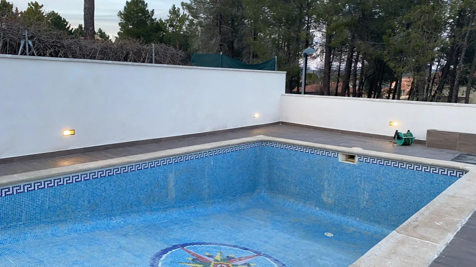Piscina residencial con borde de piedra y pavimento exterior