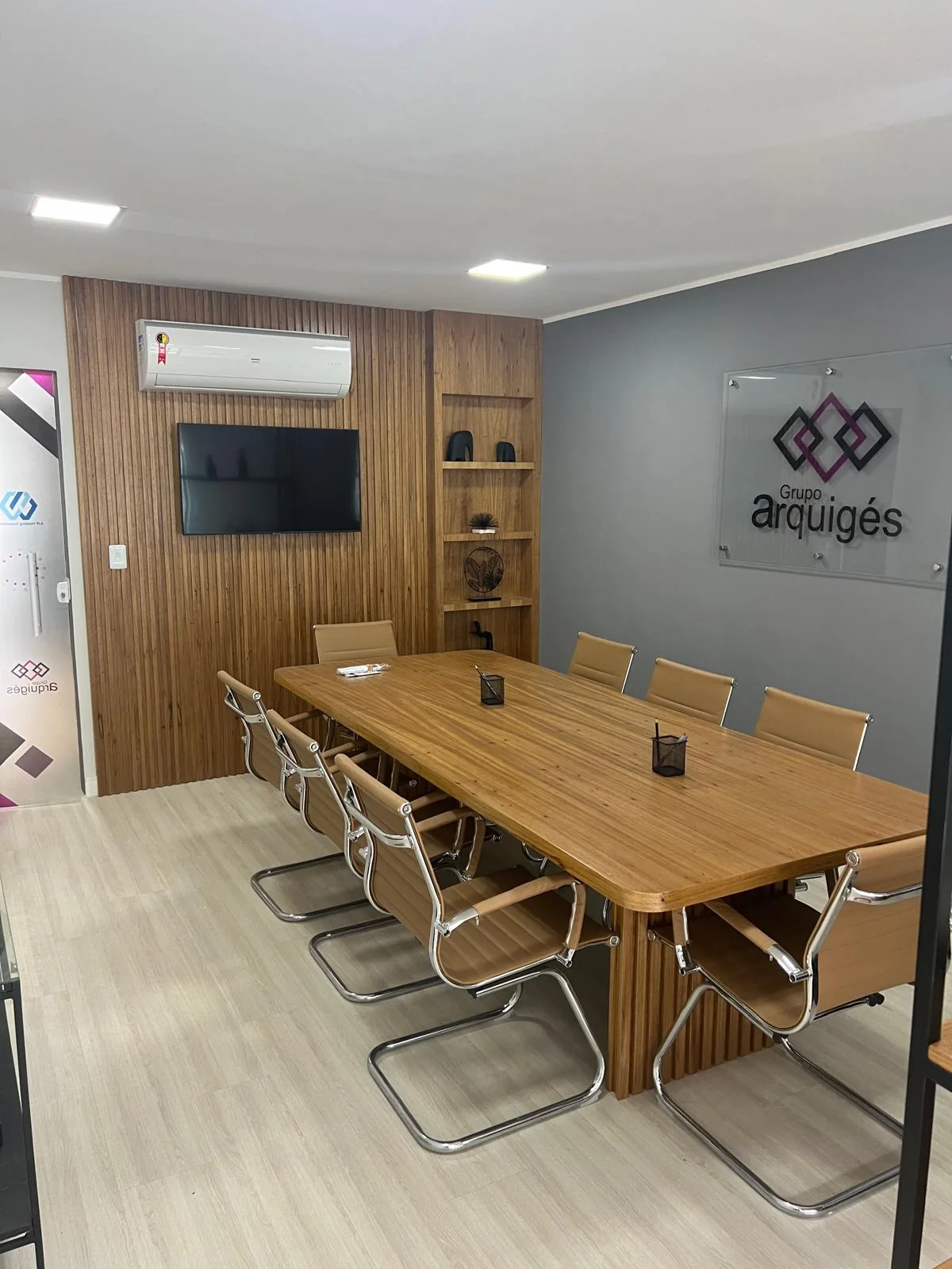 Sala de reuniones de Grupo Arquigés con mesa de madera y panelado corporativo