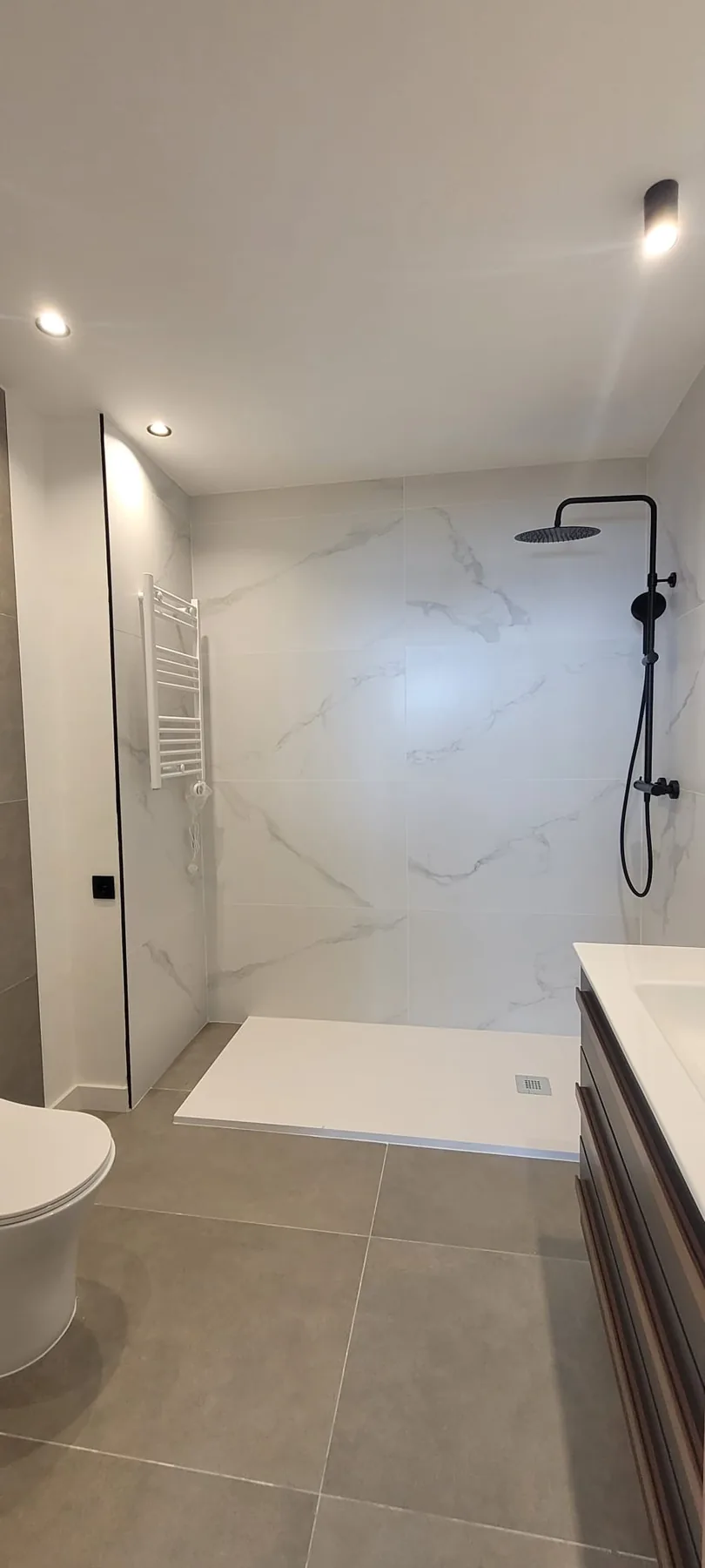 Detalle de baño renovado con ducha abierta y grifería negra