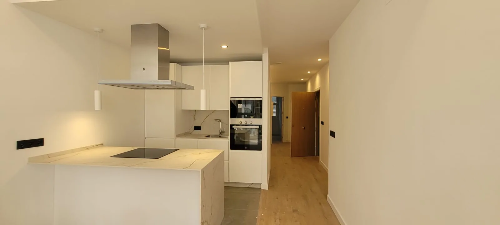 Cocina reformada de estilo contemporáneo, con isla y mobiliario blanco